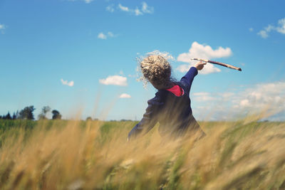 Woman with arms raised on field against sky