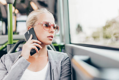 Portrait of young woman wearing sunglasses while sitting in car