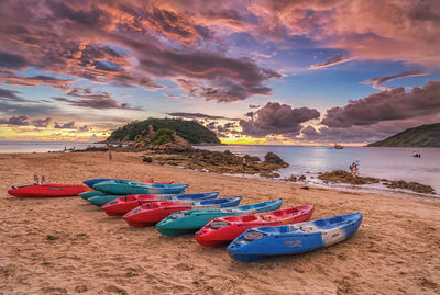 Boats moored on beach against sky during sunset