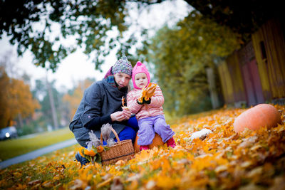 Portrait of mother and daughter over autumn leaves at public park