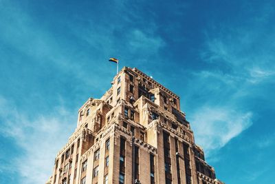 Low angle view of building with lgbtq flag against cloudy sky