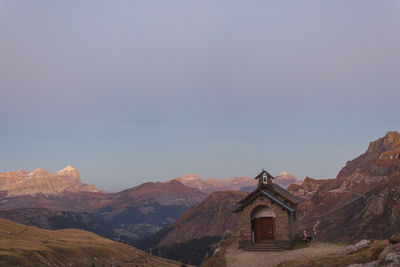 Temple against building and mountains against clear sky