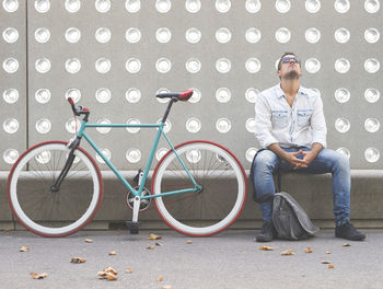 Full length of a man sitting with bicycle