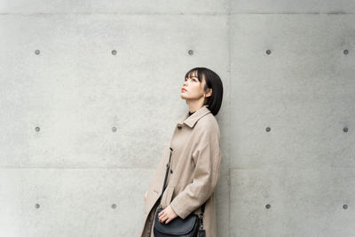 Young woman standing against wall