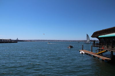 Boats in calm sea against clear blue sky