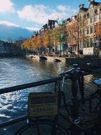 Information sign by canal in city against sky