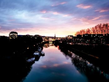 Reflection of illuminated buildings in river at sunset