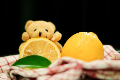 Close-up of hand holding orange fruit against black background