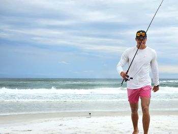 Man standing at beach against sky