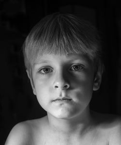 Portrait of shirtless boy against black background