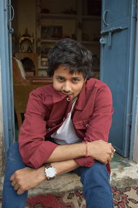 Portrait of smiling man sitting by door