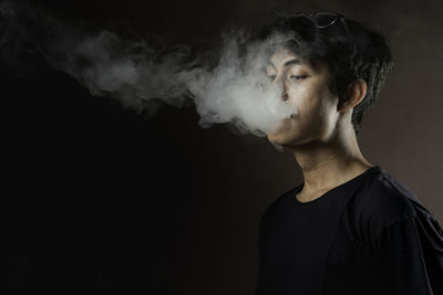 Young man looking away against black background