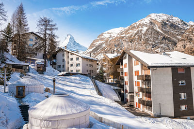 View of huts in snow covered town overlooking matterhorn mountain during winter