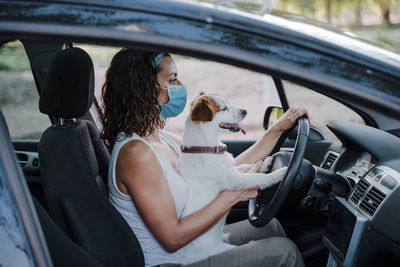 Women wearing mask sitting with dog in car