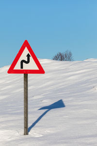 Road sign against clear sky during winter