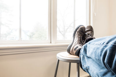 Low section of man sitting on window