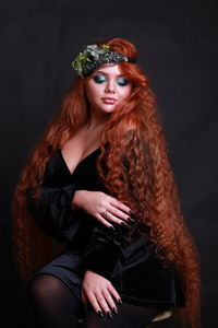 Young woman with redhead sitting against black background