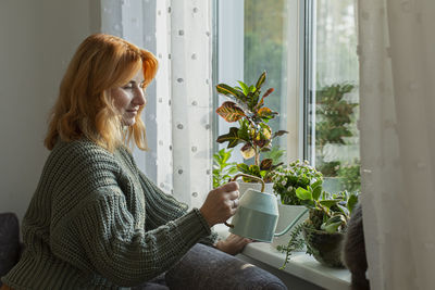 Woman watering house plants at the window