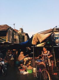 People at market stall against clear sky