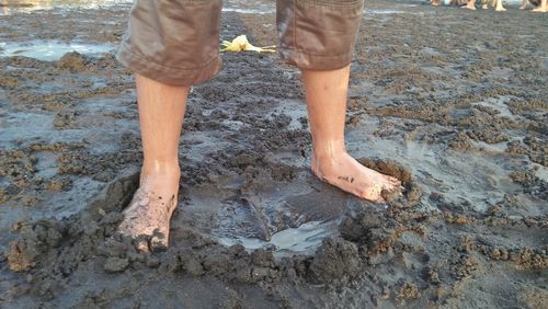 Low section of man standing on mud