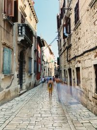 Rear view of woman walking on street amidst buildings