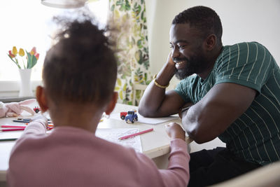 Smiling father sitting with daughter at table