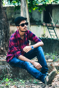 Young man wearing sunglasses sitting outdoors