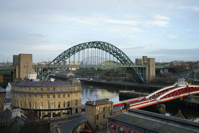 Bridge over river in city against sky