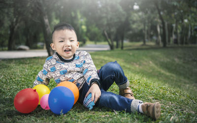 Full length of cute boy sitting on grass