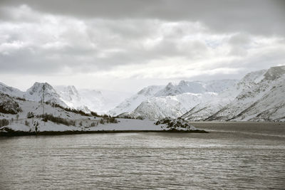 Scenic view of lake by snowcapped mountains against sky