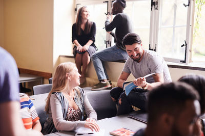 Happy woman looking at man holding book in language class