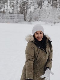 Portrait of smiling young woman standing on snow covered land