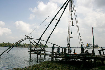 Fishermen fishing at sea shore against sky