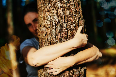Cropped hands of woman holding tree trunk