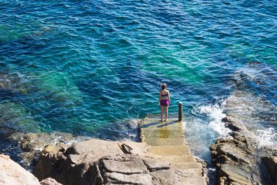 High angle view of man standing on rock by sea