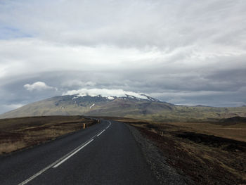 Scenic view of road by mountains against sky