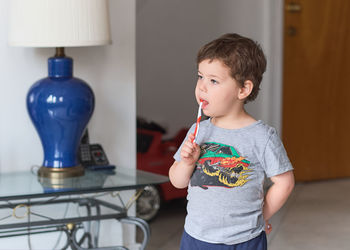 Cute toddler is brushing his teen in the livingroom