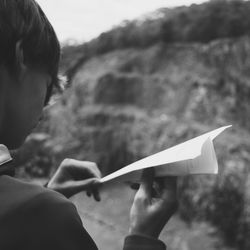 Cropped image of boy holding paper airplane