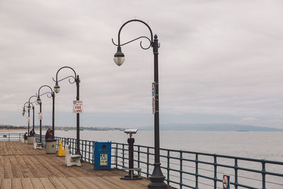 Street light by sea against sky