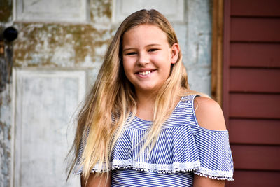 Portrait of smiling woman standing against wall