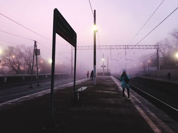 People on railroad station platform during foggy weather at dusk