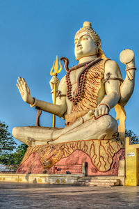 Statues against building against clear blue sky