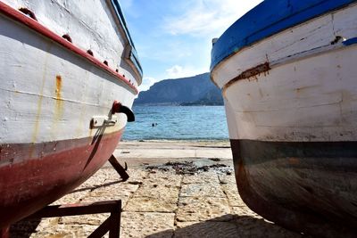 Sailboats moored on sea shore against sky