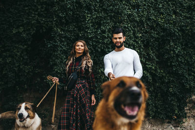 Young attractive couple walking their dogs on a leash in the streets of barcelona, spain