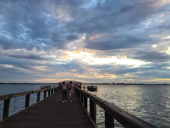 Pier over sea against sky during sunset