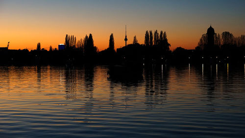 Silhouette of buildings in lake during sunset