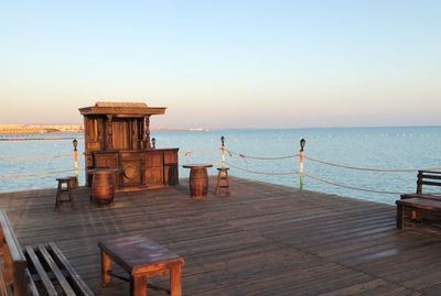 Pier on sea against clear sky during sunset