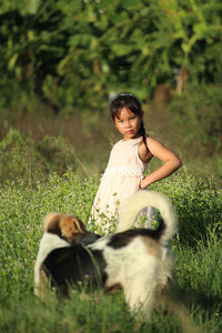 Portrait of girl standing by dog on land