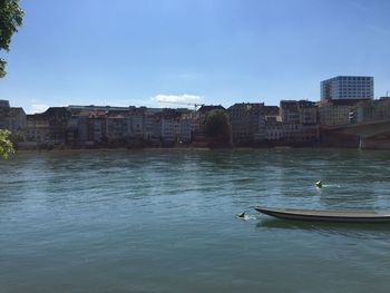 Buildings by river against sky in city