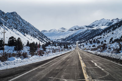 Road amidst snowcapped mountains against sky